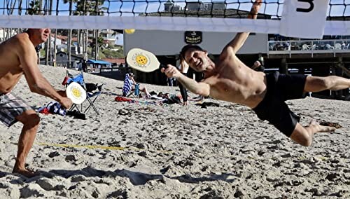 Two men playing paddleball on a sandy beach.