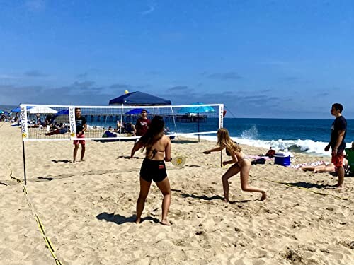 People playing beach volleyball by the ocean.