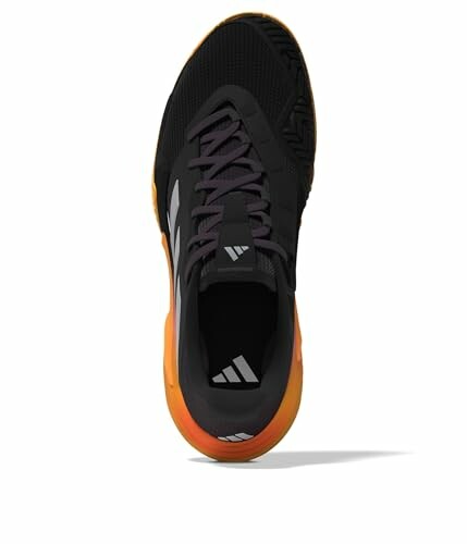 Black sneaker with orange sole viewed from top