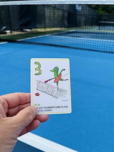 Hand holding a card with a number 3 on a tennis court