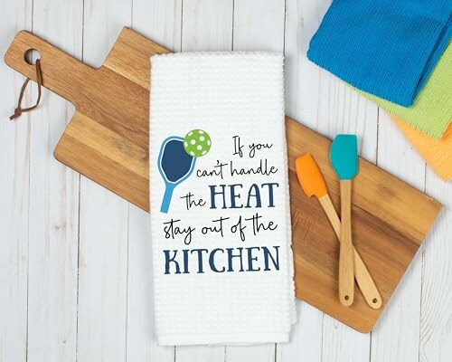 Decorative kitchen towel with a humorous quote on a wooden cutting board.