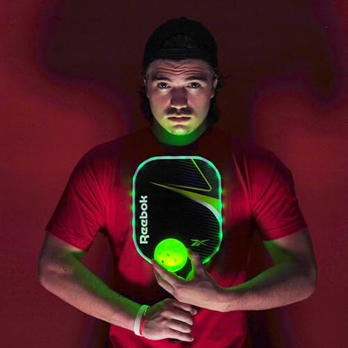 Person holding a paddle and ball with glowing green light, wearing a red shirt.