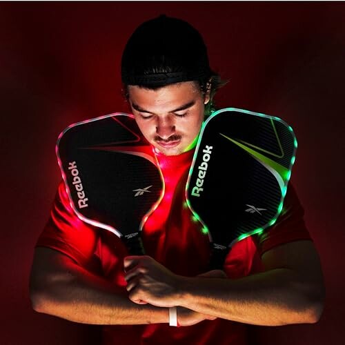 Man holding two glowing Reebok racquets