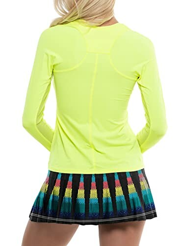 Person wearing a neon yellow long-sleeve top and multicolor skirt, back view.