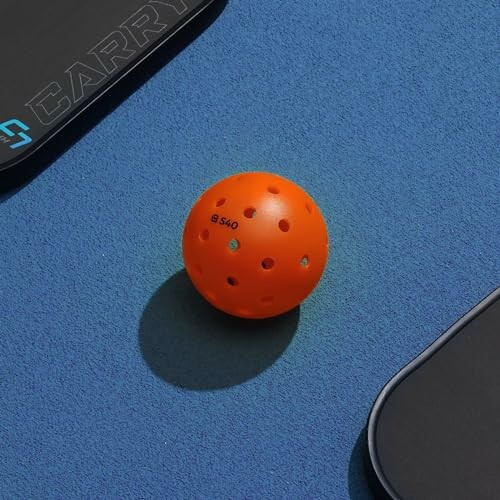 Orange perforated ball on blue sports court.