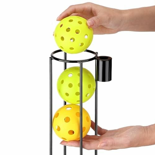 Hands placing pickleball balls in a metal holder.