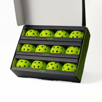 Box of green pickleball balls with holes