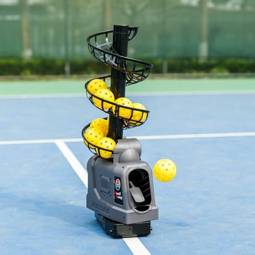 Pickleball machine on a tennis court with yellow balls.