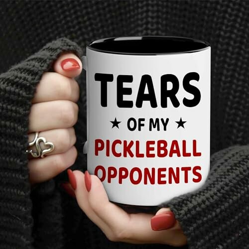 Person holding a mug with text 'Tears of my pickleball opponents'.