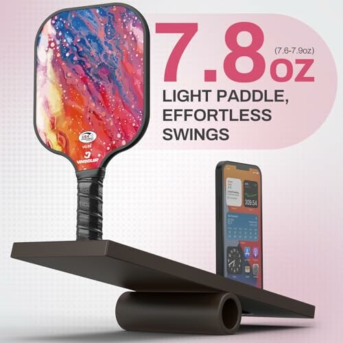 Pickleball paddle balanced with a smartphone on a seesaw, highlighting its light weight of 7.8 oz.