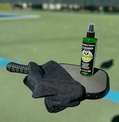 Pickleball paddle with cleaner spray and cloth on a court.