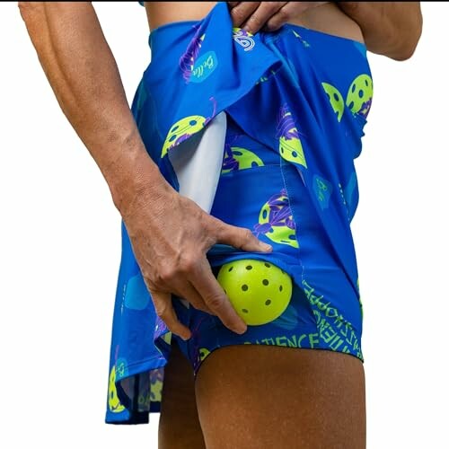 Person showing a pickleball in a pocket of a blue skirt.