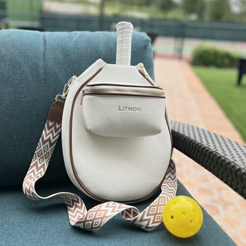 Tennis bag with racket handle and yellow ball on outdoor chair