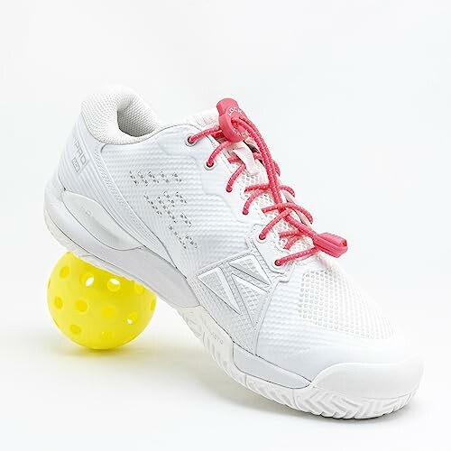 White tennis shoe with pink laces on a yellow perforated ball