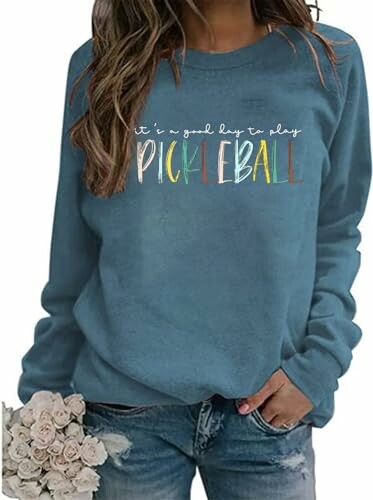 Woman wearing blue 'It's a good day to play Pickleball' sweatshirt holding flowers