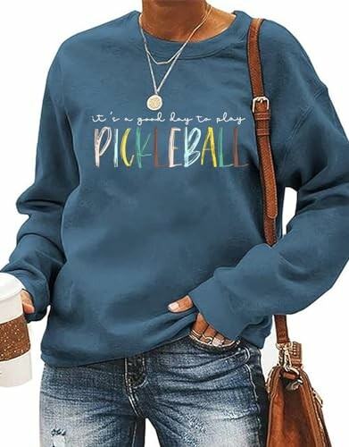 Woman in blue pickleball sweatshirt holding coffee