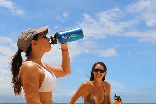 Two women at the beach drinking from water bottles